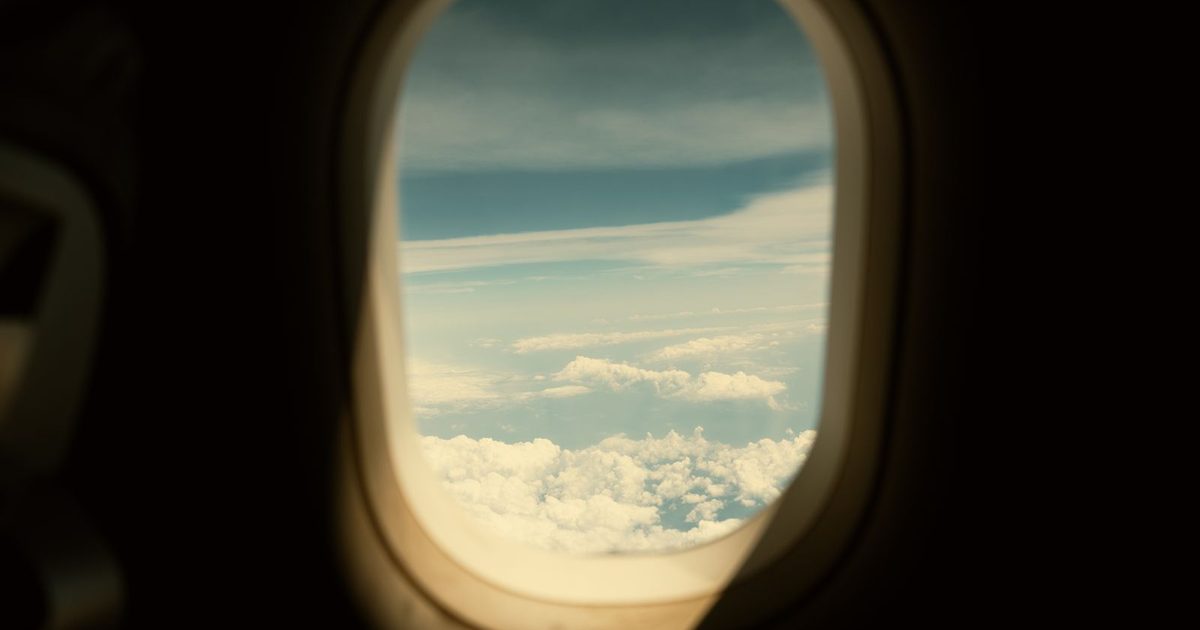Clouds and blue sky through an airplane window