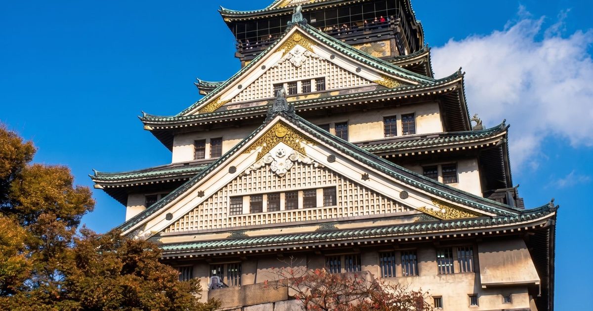 Osaka Castle and autumn leaves under a blue sky